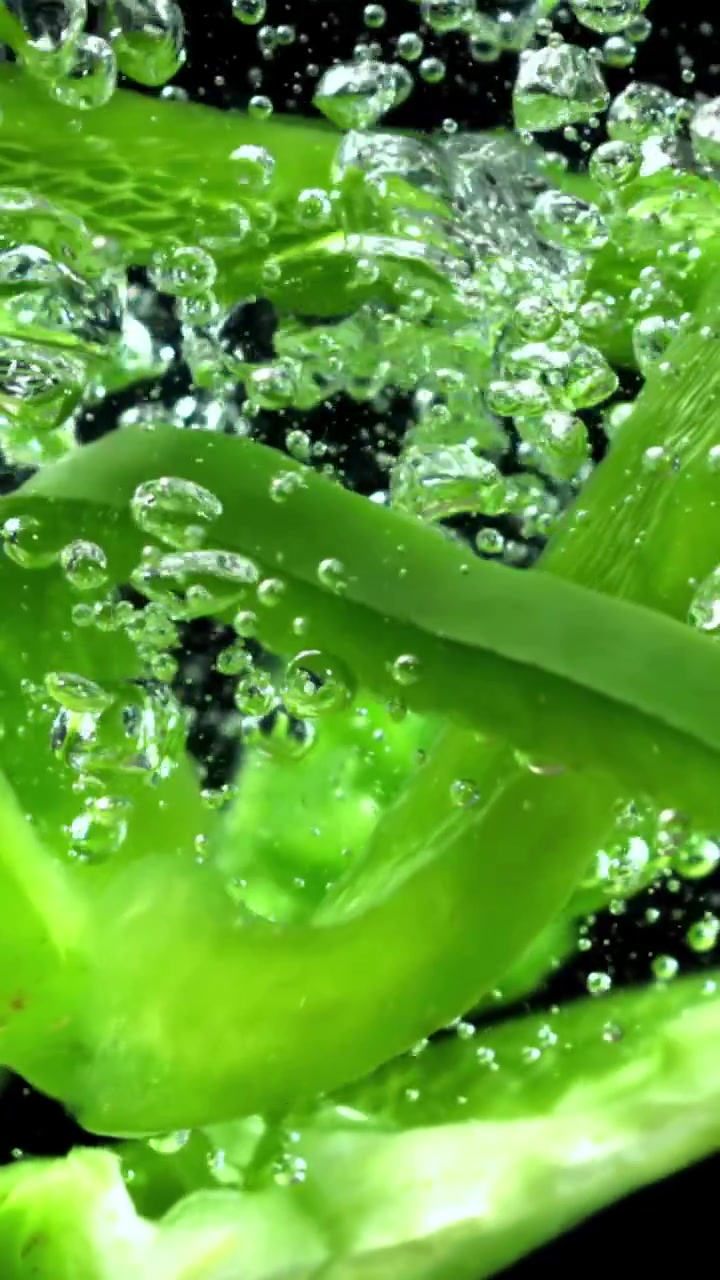 Fette di peperone verde fresco che schizzano nell'acqua