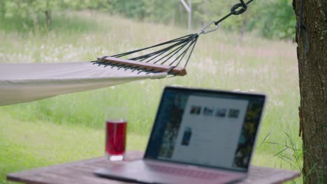 homeoffice setting with laptop on table in garden next to hammock