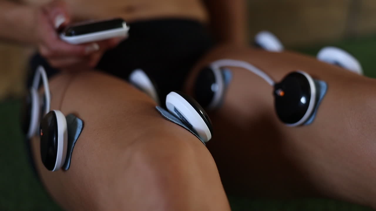 imágenes de primer plano de almohadillas de masaje de electrovibración que se utilizan en las piernas de un atleta