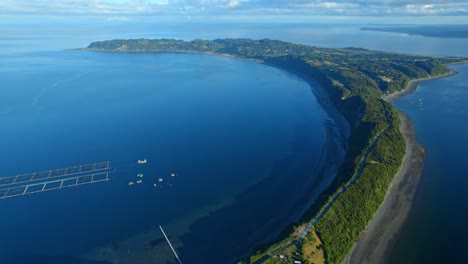 Luftaufnahme-Der-Insel-Lemuy-Mit-Klarem-Himmel-Und-Ruhiger-See,-Boote,-Die-In-Der-Nähe-Eines-Stegs-Schwimmen,-Heiterer-Blick-Auf-Die-Natur