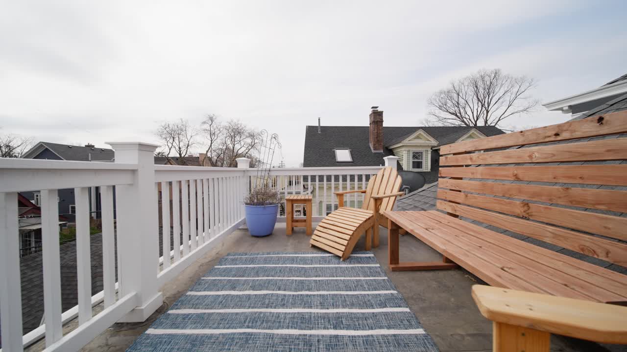 Peaceful rooftop patio with wooden chairs and a striped rug overlooking suburban homes