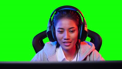 asian gamer woman playing game online and looking at screen on pc computer at home. asian woman controlling console with mouse and keyboard. green screen or chroma key background.