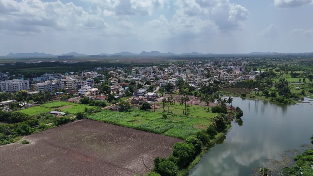 Bird's-eye view of Vijayawada, where the dense city infrastructure fades into lush greenery and the distant hill.