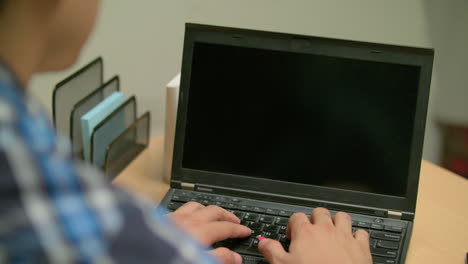 por encima del hombro, un hombre escribiendo en su computadora portátil
