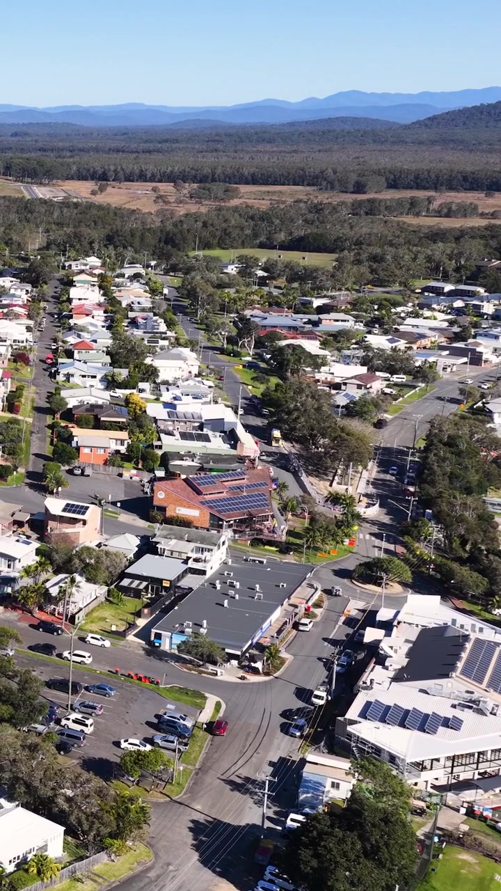 Ripresa aerea con drone di un quartiere residenziale ed edifici commerciali a Crescent Head, Australia