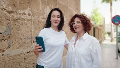 two women mother and daughter making selfie by smartphone at street