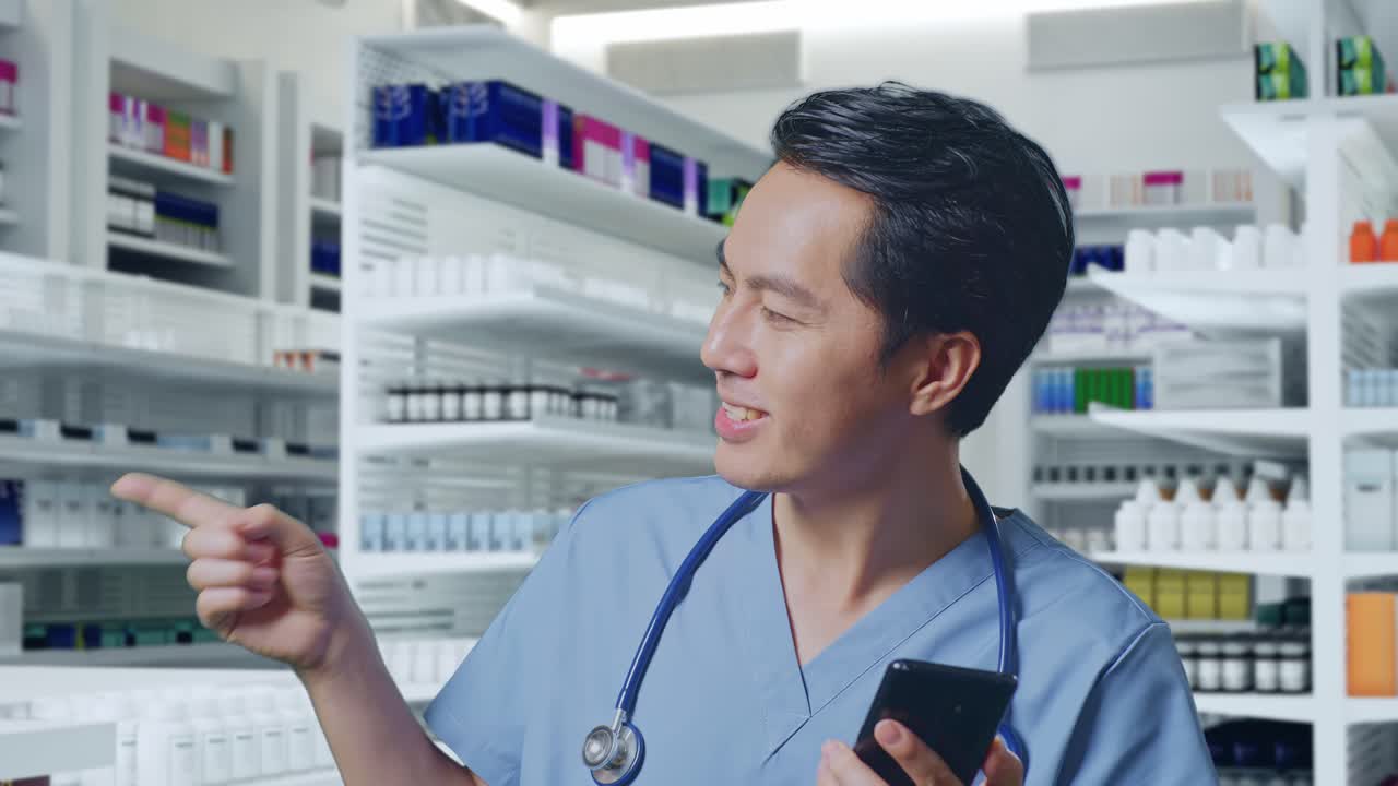 스마트폰을 사용하고 약국에 서 있는 동안 으로 가리키는 스테토스코프를 가진 아시아 남성 의사의 클로즈업