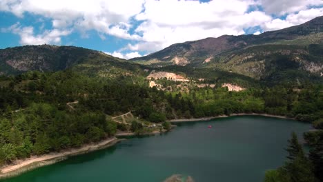 sliding right aerial parallax shot of lake tsivlou view from above with green mountains surrounding peacefully the natural waters on an overcast cloudy day