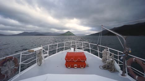 vorderansicht des kreuzfahrtschiffes mit meer, hügeln und bewölktem himmel im hintergrund