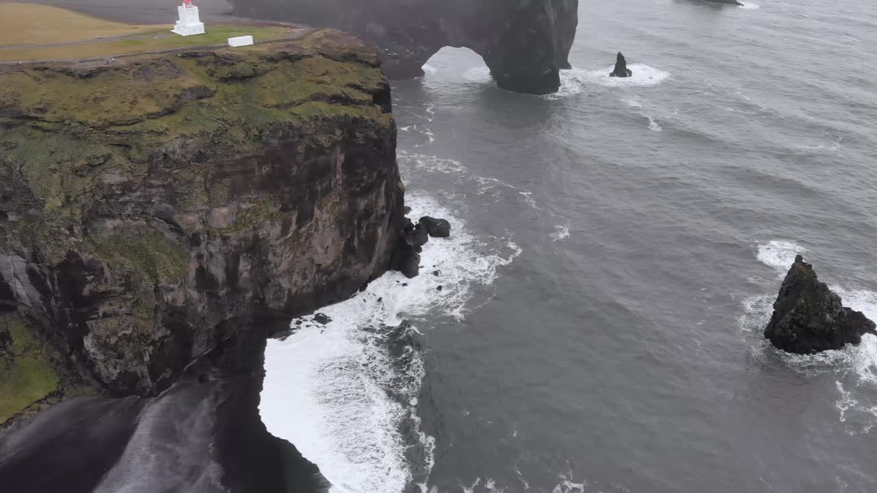 극적인 절벽이 있는 아이슬란드 해안의 등대가 있는 디르홀레이 관점의 항공