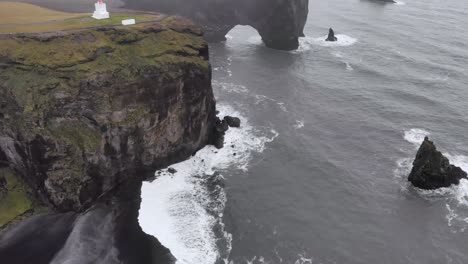 Antena-Del-Mirador-Dyrhólaey-Con-Un-Faro-En-La-Costa-De-Islandia-Con-Espectaculares-Acantilados