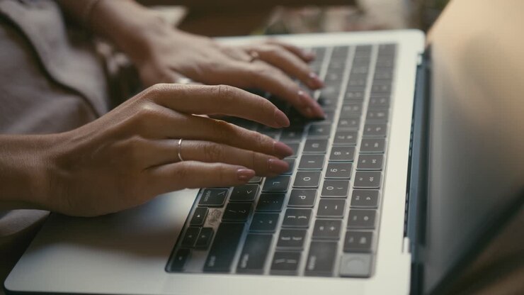 Nahaufnahme von Händen, die auf einer Laptop-Tastatur tippen