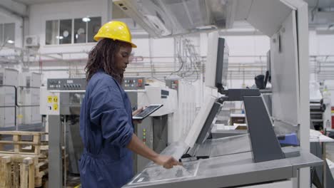 confident black factory worker operating industrial machine