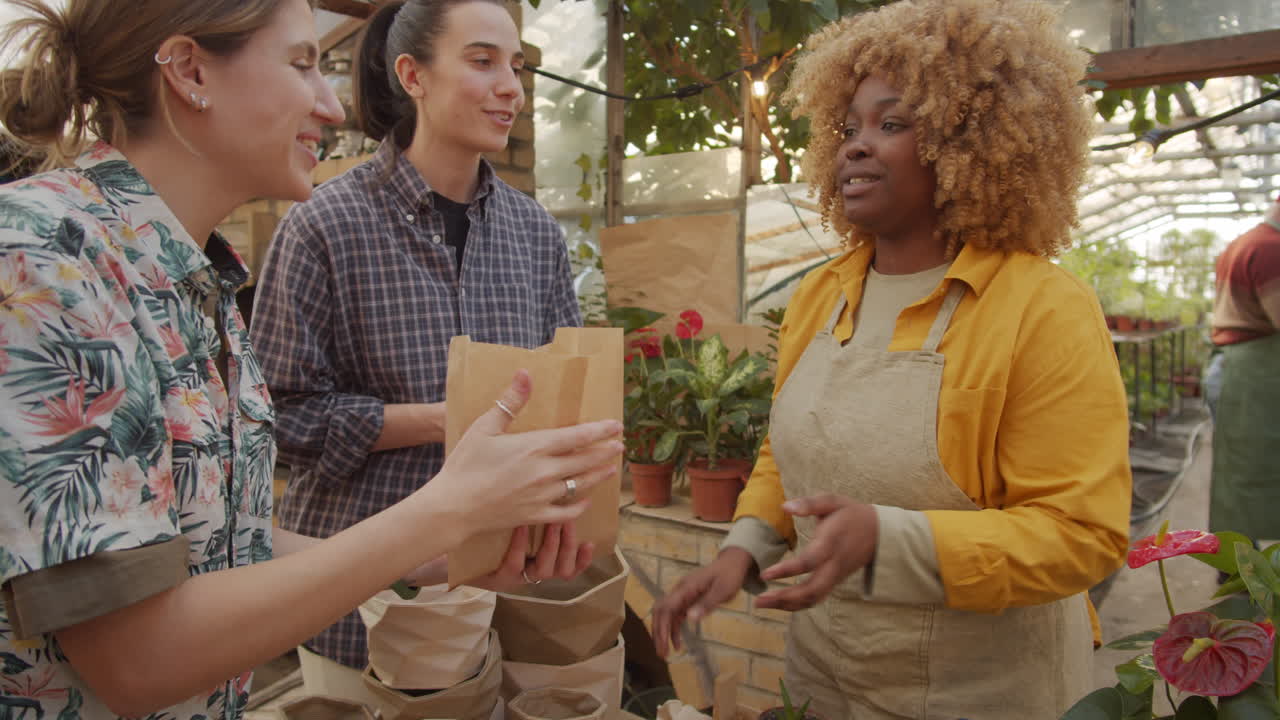 mujeres alegres comprando plantas de interior en el mercado de flores