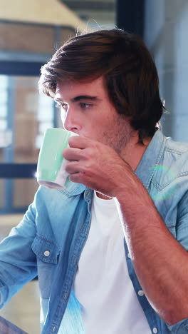 hombre tomando café mientras trabaja en la computadora