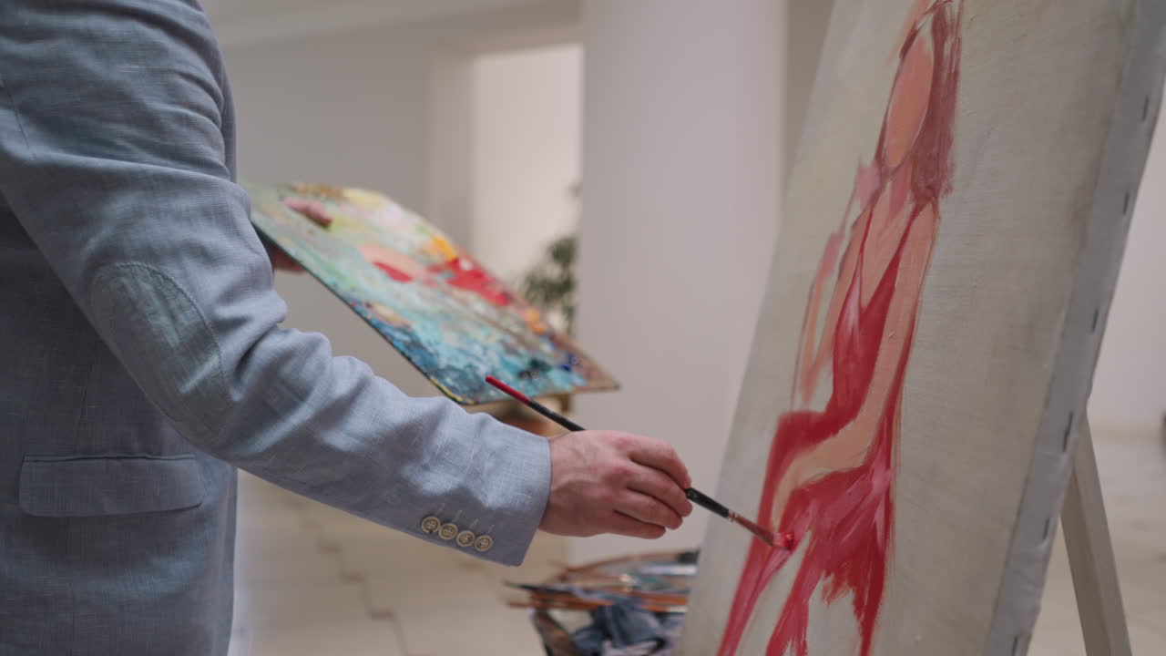 el hombre dibuja a la mujer de los sueños en primer plano en el estudio. el artista con acrilo pinta la paleta a mano trabaja sobre el retrato en el taller. el pintor crea obras de arte coloridas