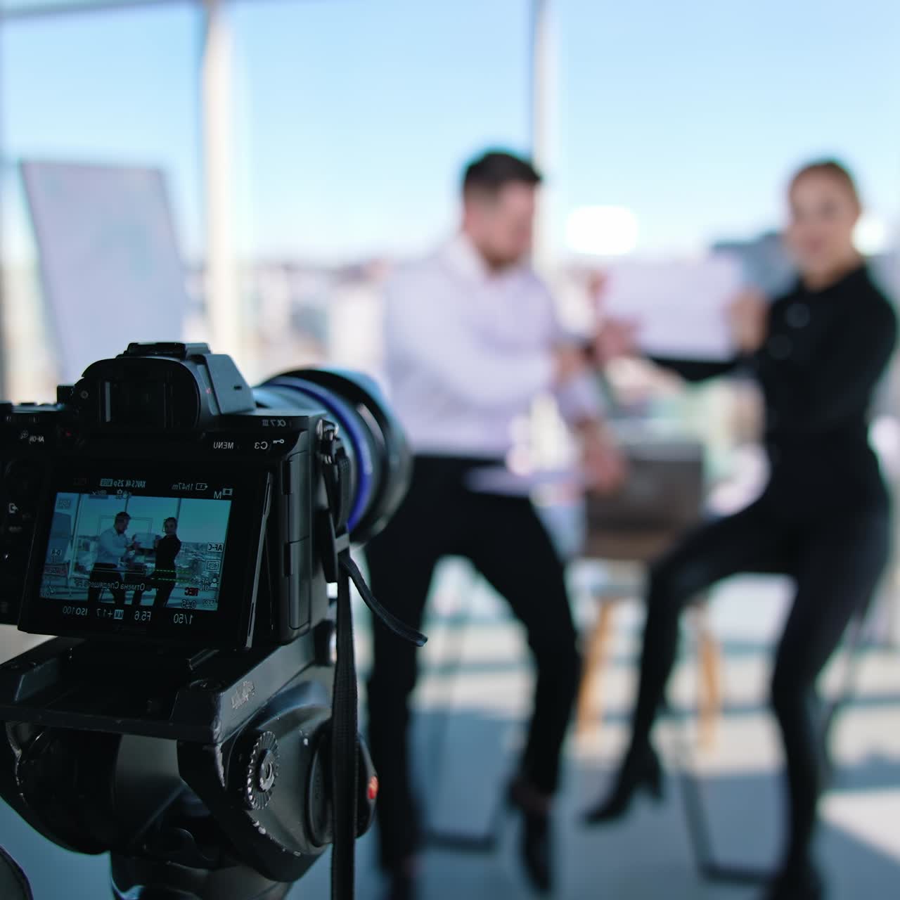 Business colleagues working together in office. Businessman is sitting at table and working on a laptop. Young woman helps a man in business. Operator recording it to the camera