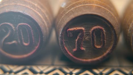 cinematic macro smooth shot of bingo wooden barrels in a row, woody figures, old numbers vintage board game, number 70, slow motion, commercial gimbal movement, dreamy lighting pan right