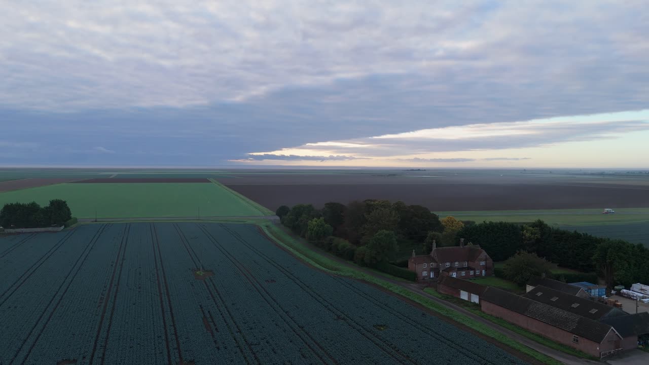 Rural aerial scene of open countryside farmland dawn or sunset blue tones. Misty uk morning in isolated landscape fresh winter autumn frosty sunrise, sunset, trees and farmhouse, green pastures
