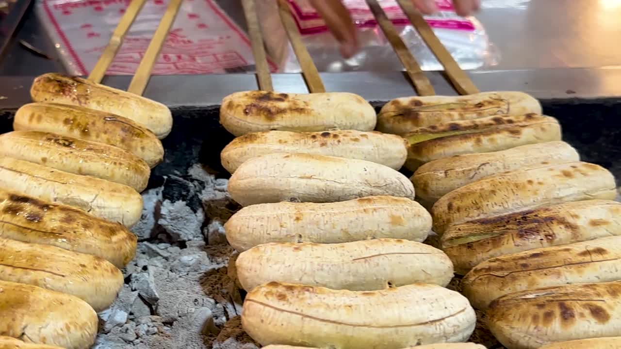 Bir pazar tezgahında kömür ateşinde ızgara muzlar