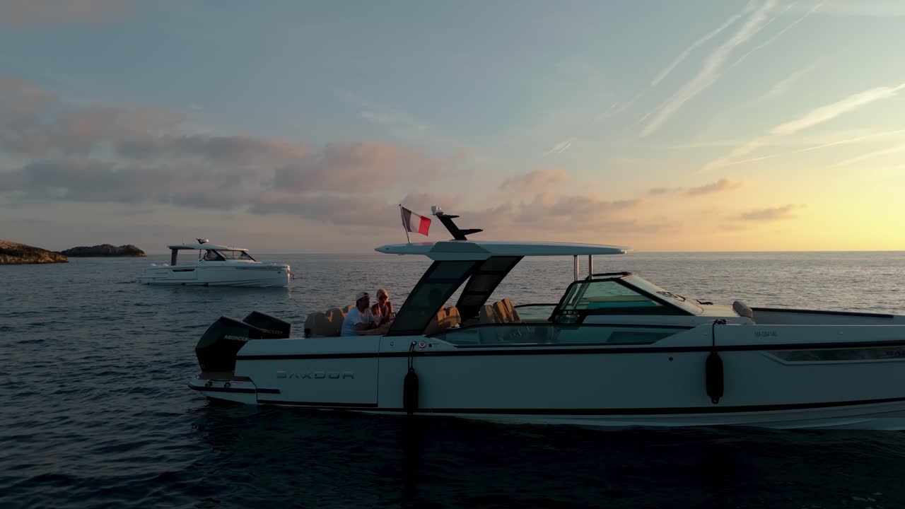 People enjoy a relaxing time on a boat floating in calm waters near Nice, France, with the warm glow of sunset casting a serene ambiance over the Mediterranean Sea.