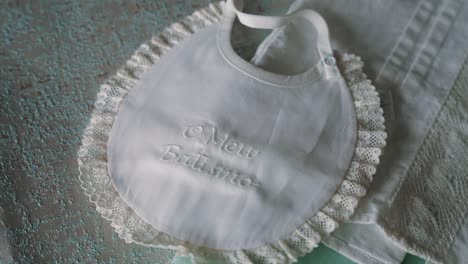close up of white baptism bib with lace trim on fabric