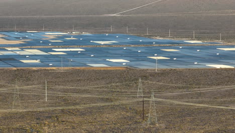 solar farm in the nevada desert revealed behind a rocky mountain, aerial reveal