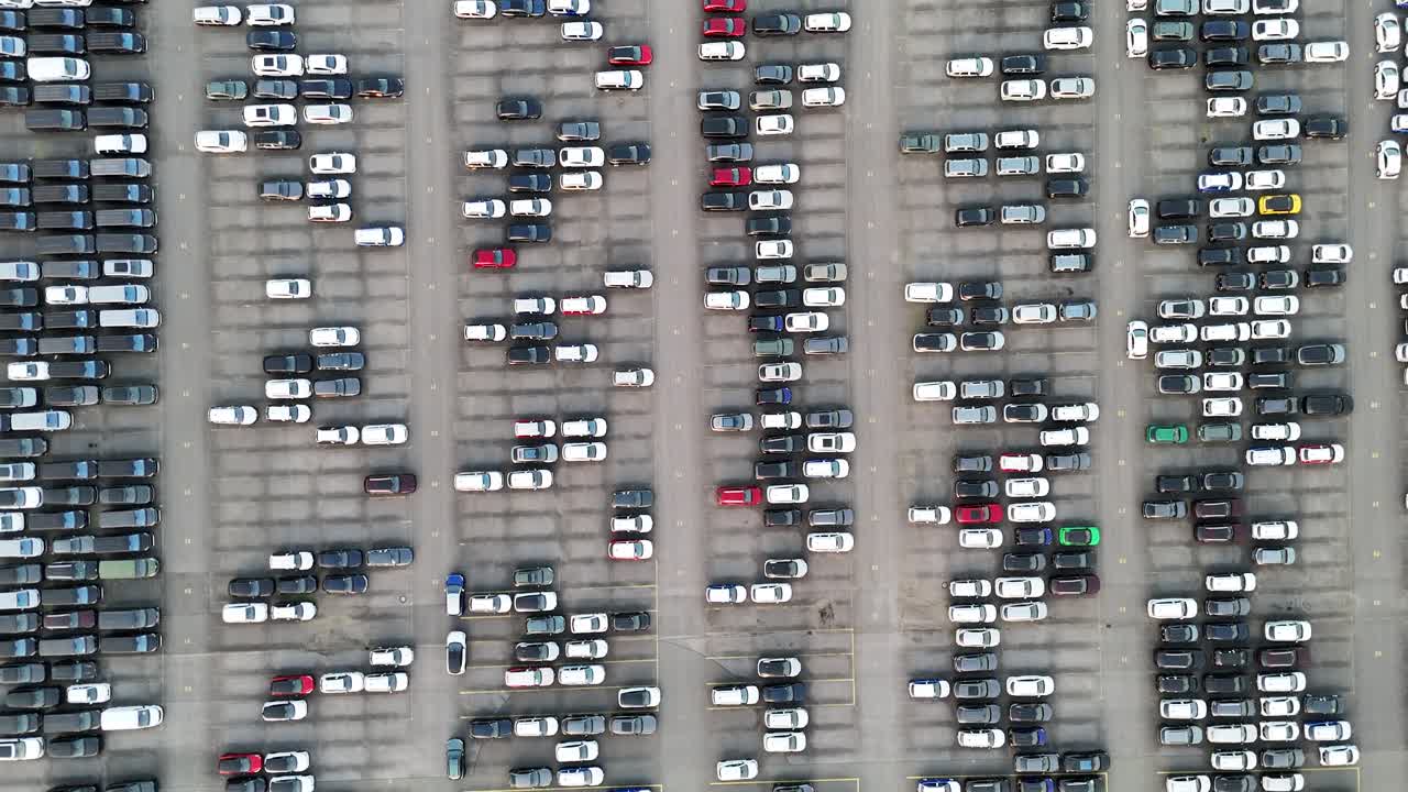 Højere luftfoto af blokke af køretøjer, varevogne og lagerlayout, der understreger storskala bildistribution.
