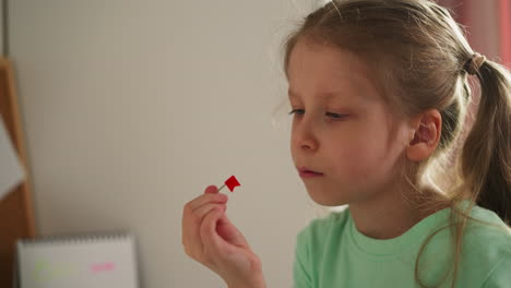 tired schoolgirl looks at pin with red flag intently spinning