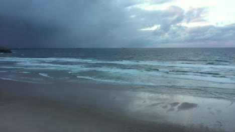 Aerial-view-over-a-mirroring-beach-and-waves-crashing-the-coast-of-North-Spain---tracking,-pan,-drone-shot