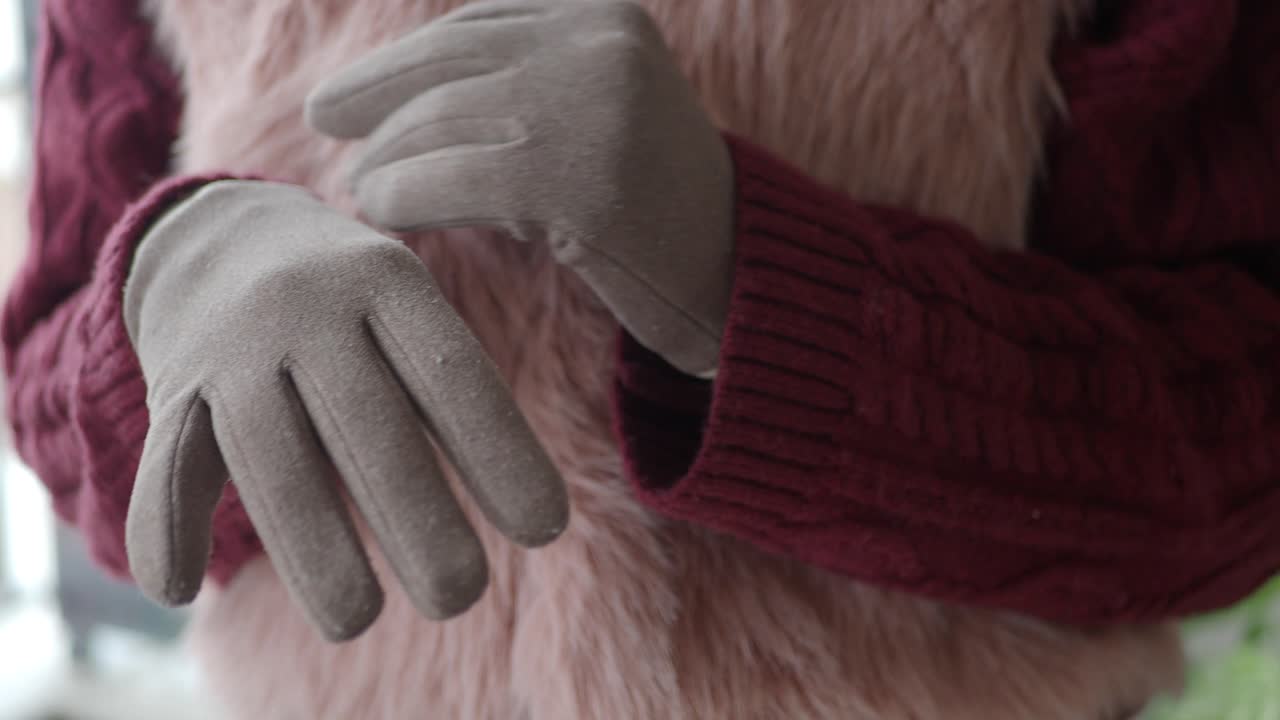 Tangan dalam Sarung Tangan Abu-Abu dengan Bulu Imitasi Merah Muda dan Sweater Burgundy