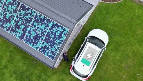 hombre cargando un coche eléctrico en un patio de la casa con electricidad de paneles solares
