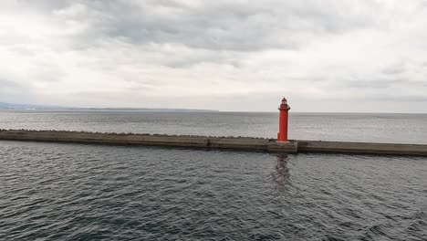 Vorbei-An-Einem-Roten-Leuchtturm-Auf-Einem-Wellenblocker-Im-Meer