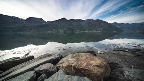 Mountains-ad-passing-clouds-are-reflected-in-the-calm-waters-of-the-fjord