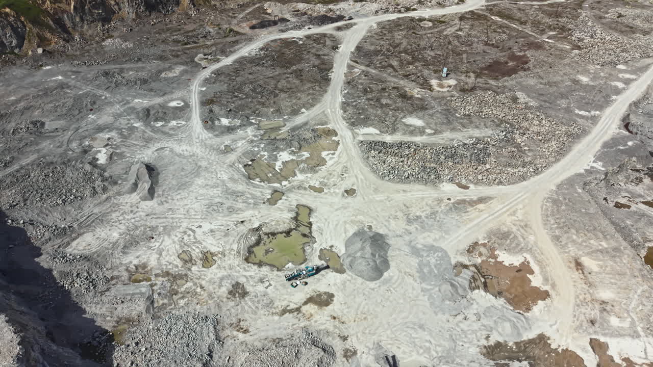 Granite quarry site showing raw materials, machinery, and land during daylight hours in a remote area