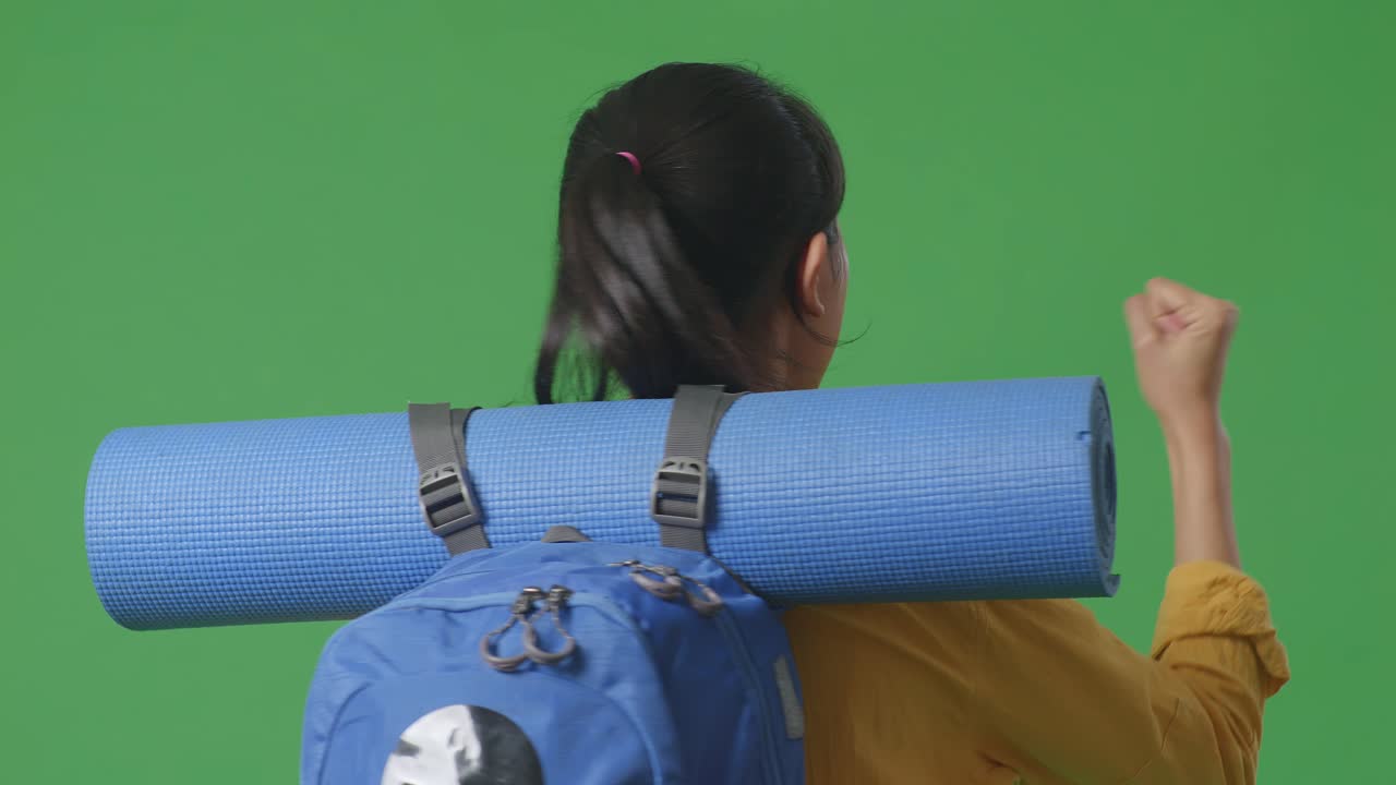 vista posterior de cerca de una excursionista femenina con mochila de montañismo gritando meta celebrando el éxito mientras estaba de pie en el fondo de la pantalla verde en el estudio