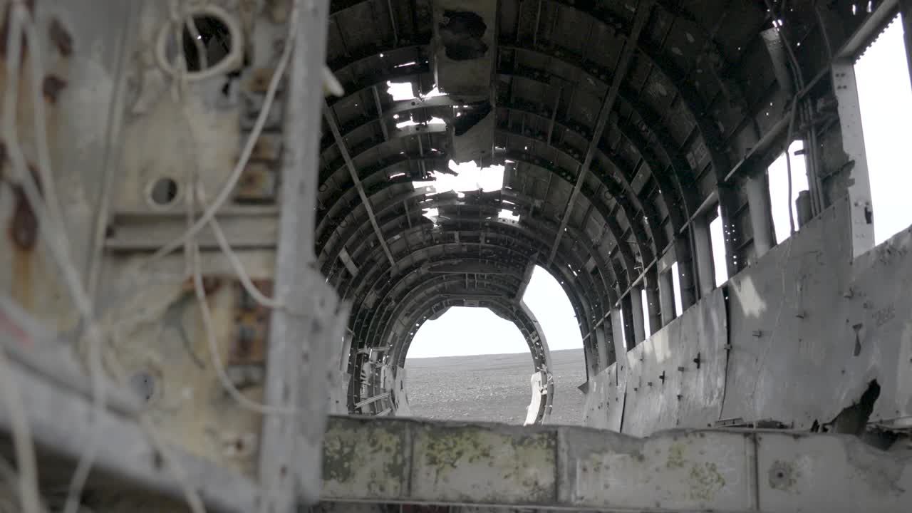 Slow motion shot of a tourist walking past the plane wreckage at S&oacute;lheimasandur