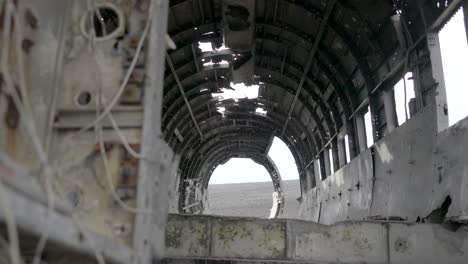 slow motion shot of a tourist walking past the plane wreckage at sólheimasandur