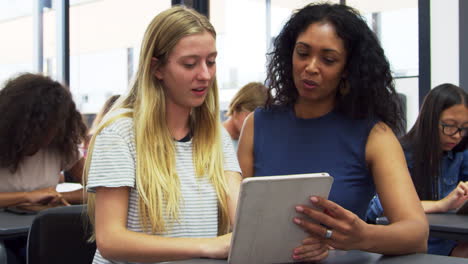 teacher helps blonde teenage schoolgirl use tablet computer