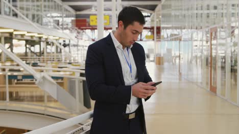 Hombre-De-Negocios-Usando-Un-Teléfono-Inteligente-En-El-Vestíbulo-De-Una-Conferencia