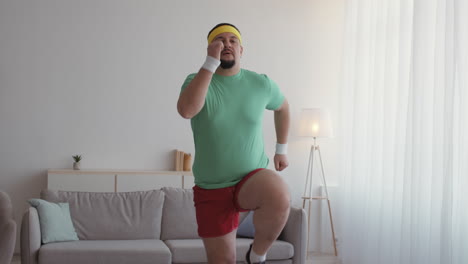과체중 인 남자 가 집 에서 점핑 잭 을 하고 있다
