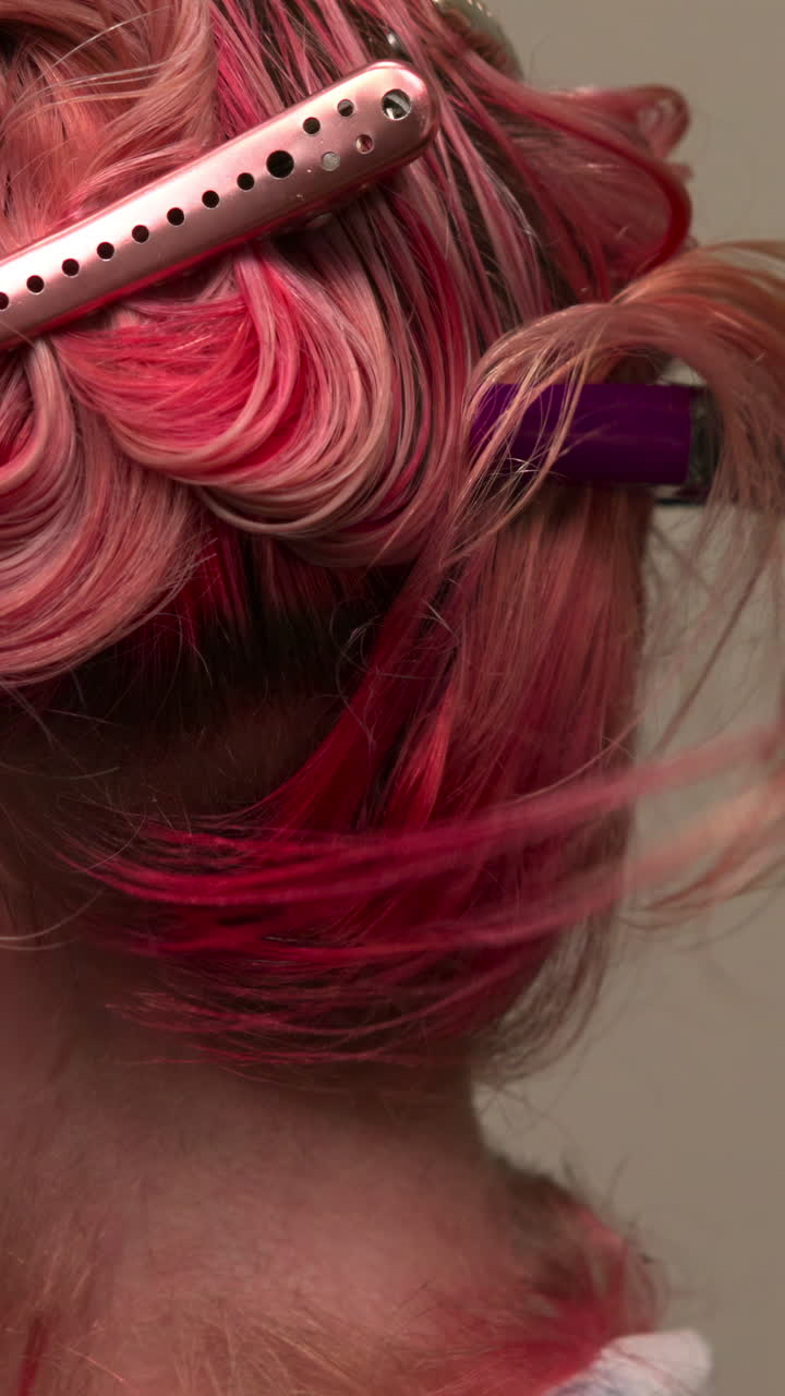 Haarstylist teilt rosa und blondes Haar mit Spangen ab