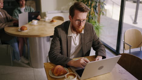 man working on laptop in coffee shop