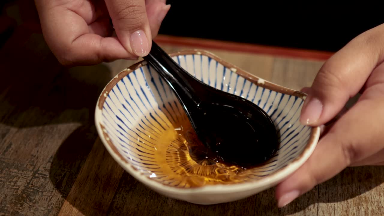 Hands stirring sauce with a black spoon