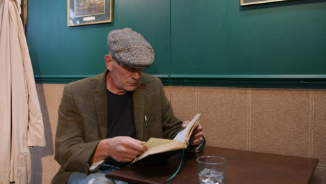elderly man reading a book in a pub