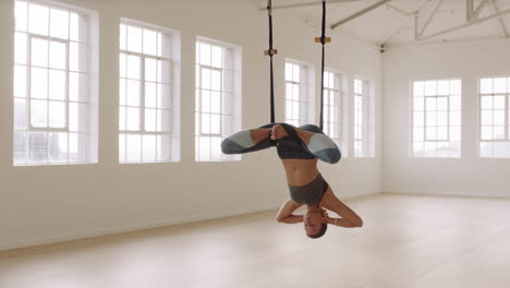 flexible woman practicing aerial yoga poses using hammock enjoying fitness lifestyle exercising in studio training meditation at sunrise