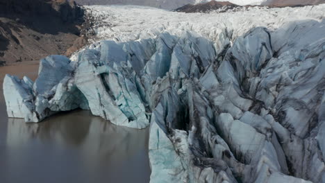 Aerial-view-floating-icebergs-of-Breidamerkurjokull-glacier-tongue-in-Iceland.-Drone-view-snow-capped-mountains-and-ice-formations-in-Vatnajokull-national-park.-Breidamerkurjokull-glacier