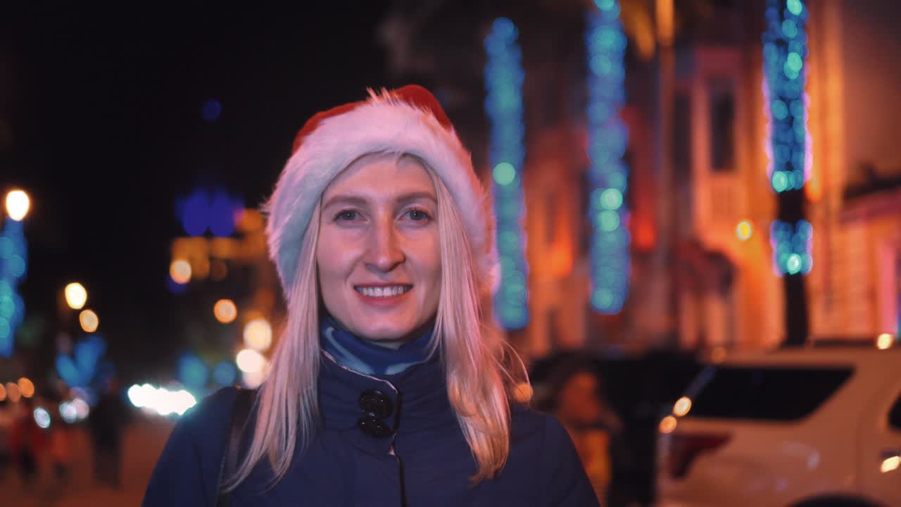 카메라에 미소 짓고 산타 모자를 입고 놀고 있는 여자의 초상화