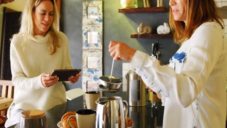 lesbian couple preparing coffee and using digital tablet in kitchen 4k