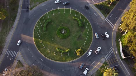 aerial top down of several cars driving in roundabout during sunset - traffic on road in big city